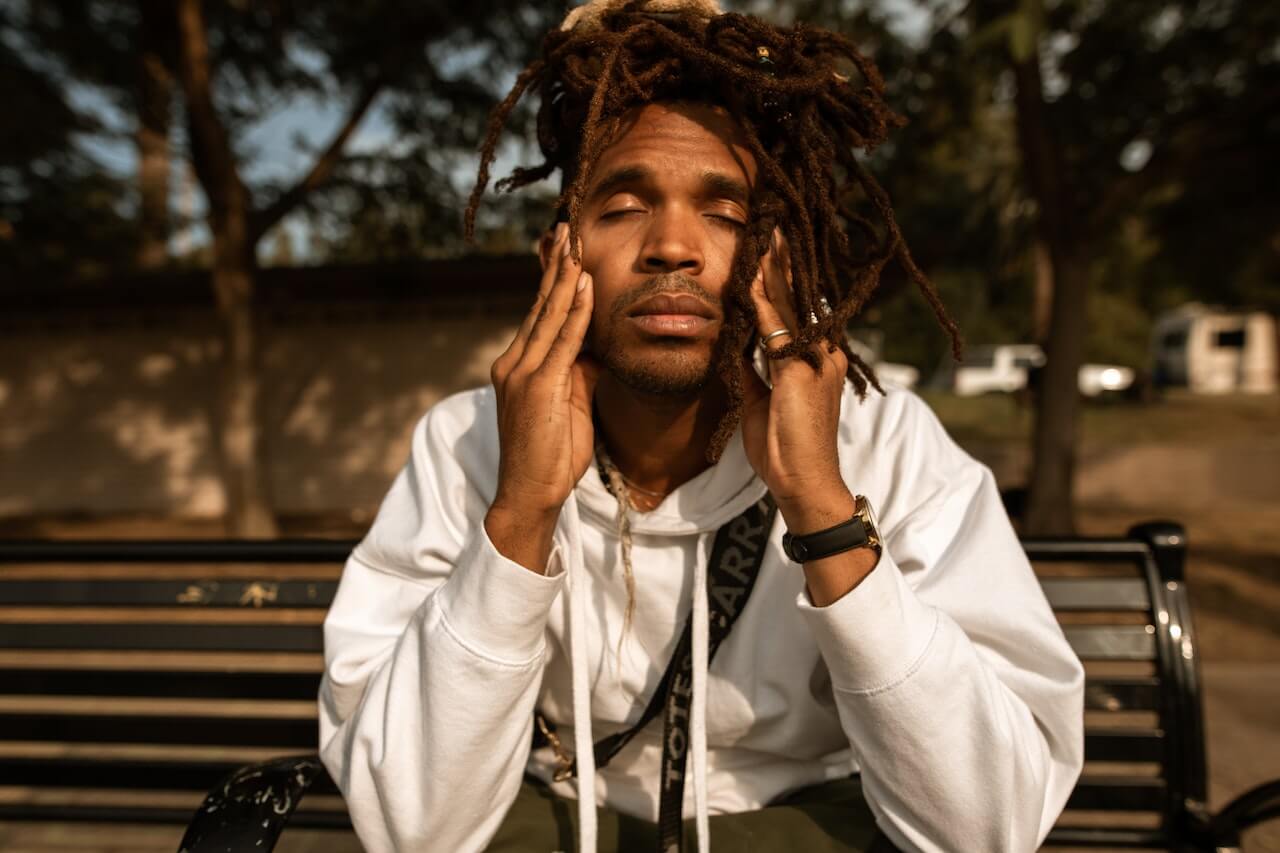 a man with his eyes closed sitting on a bench