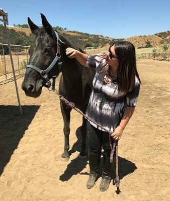 a woman standing next to a horse