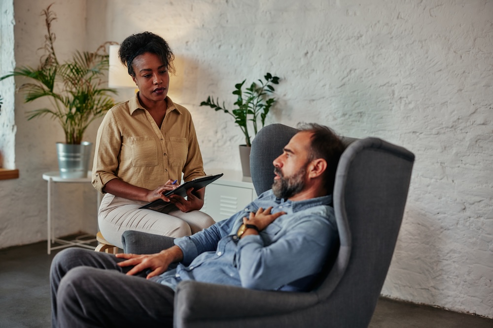 Female therapist sitting with male patient in therapy session