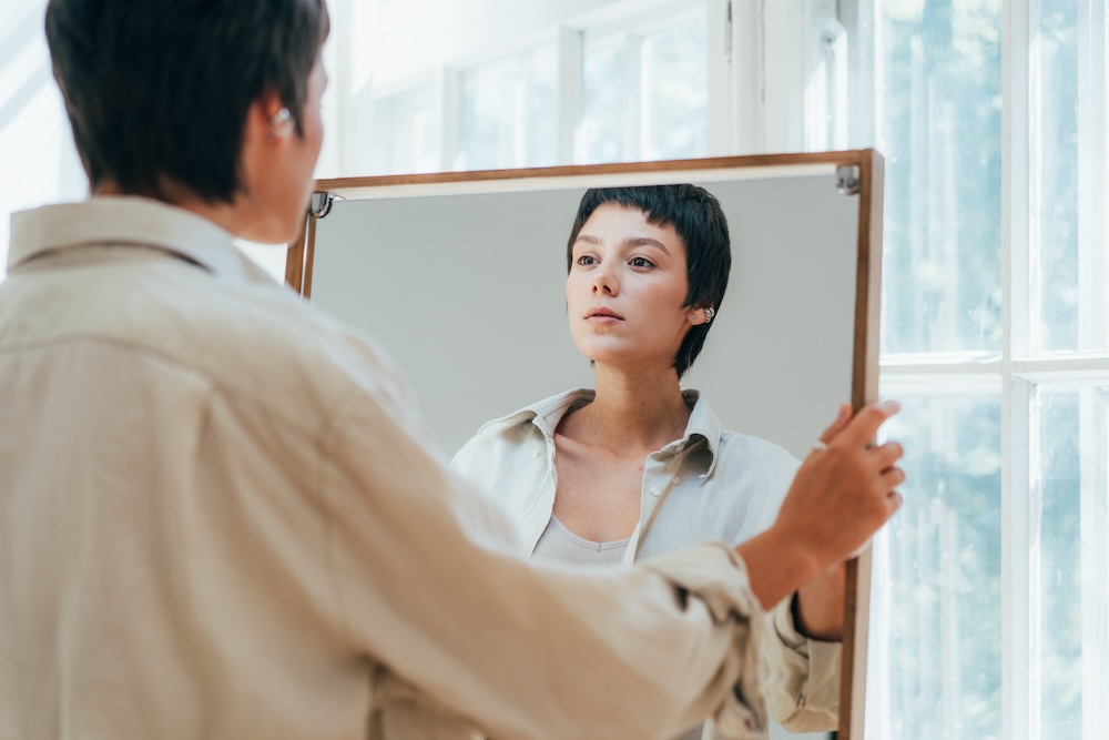 A young woman peers at her reflection in the mirror.