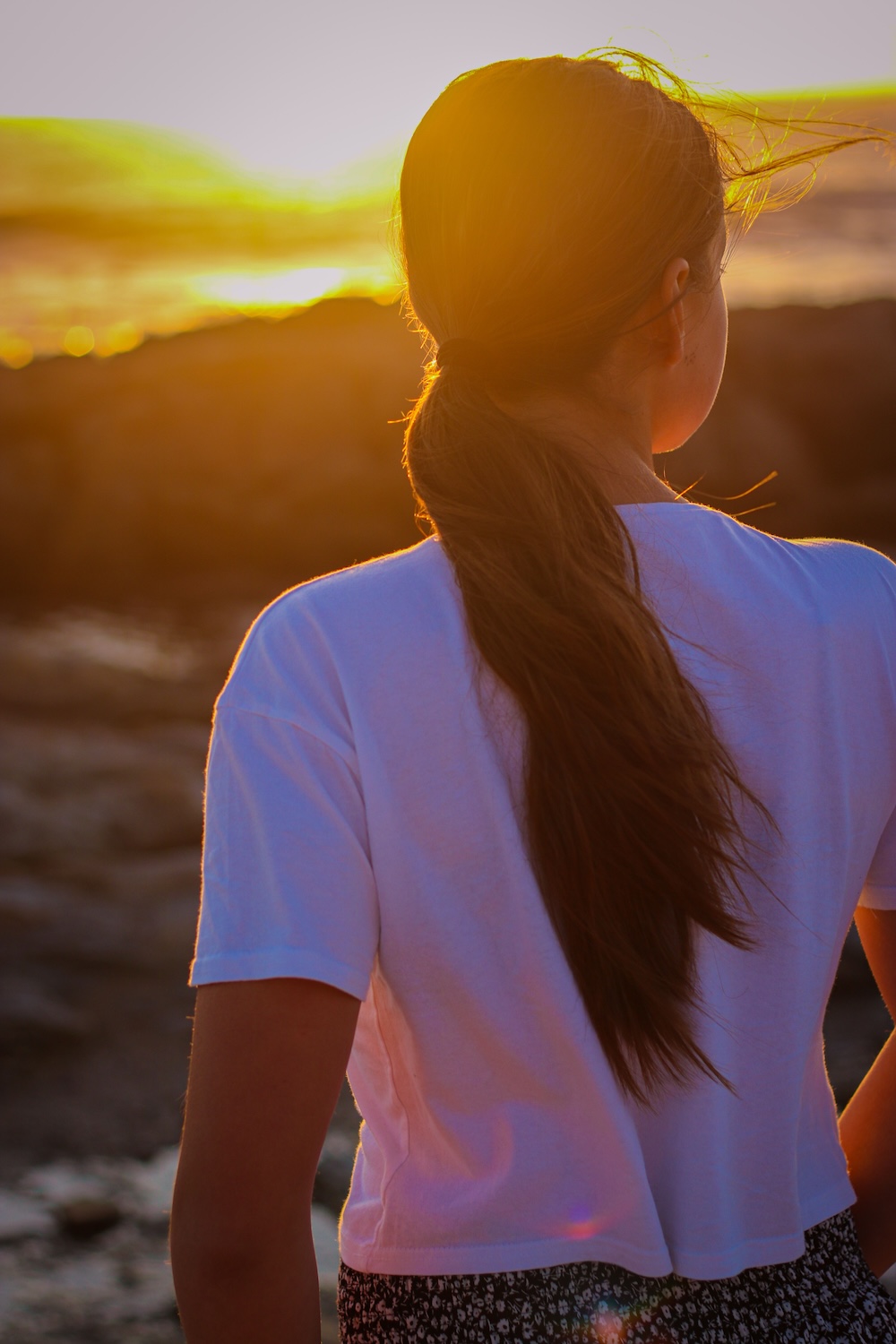 Young woman looking at the sea during the sunrise in the morning