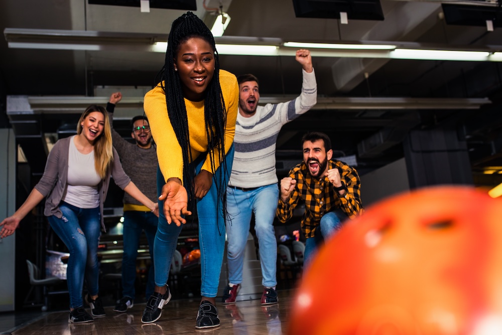 Group of friends enjoying sober time together laughing and cheering while bowling alley.