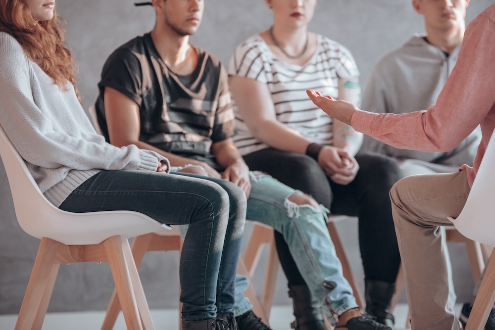 Group of individuals sitting in chairs during group therapy session