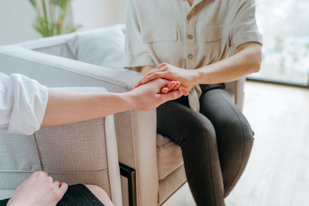 Mental health professional holding the hand of a client during DBT session in residential treatment.