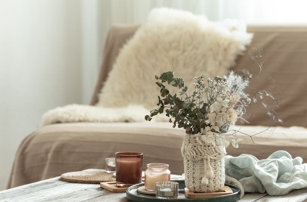 Cozy home composition with candles and a bouquet of dried flowers in a vase in the interior of a room in transitional living home.