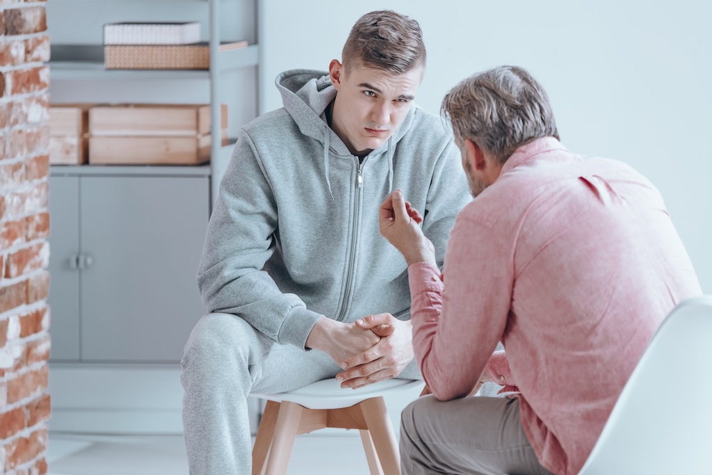 Young man talking with counselor about his issues during residential treatment.