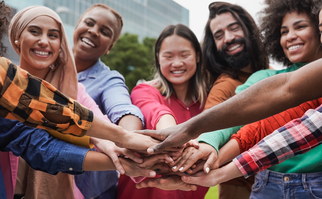 Group of young diverse people stacking hands in support of their community