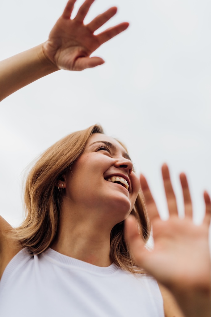 Young woman dancing outdoor gesturing with hands feeling free smiling having fun