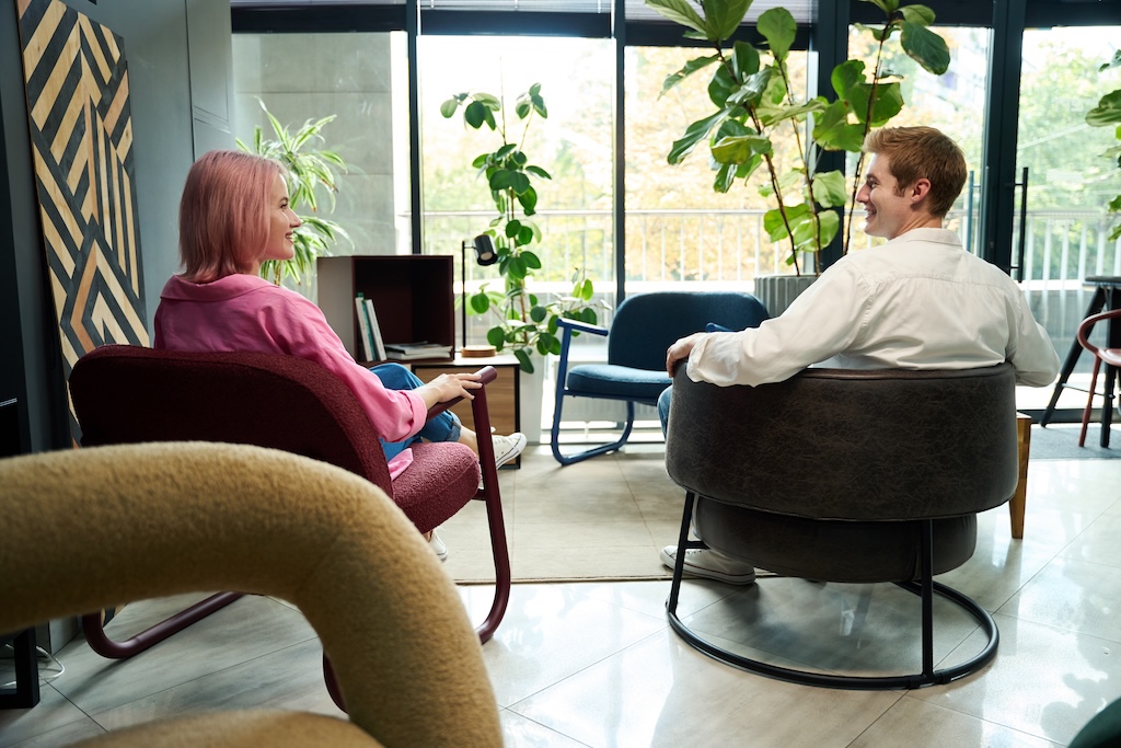 Smiling therapist sitting in individual therapy office with male client during residential treatment for prescription drug addiction program.