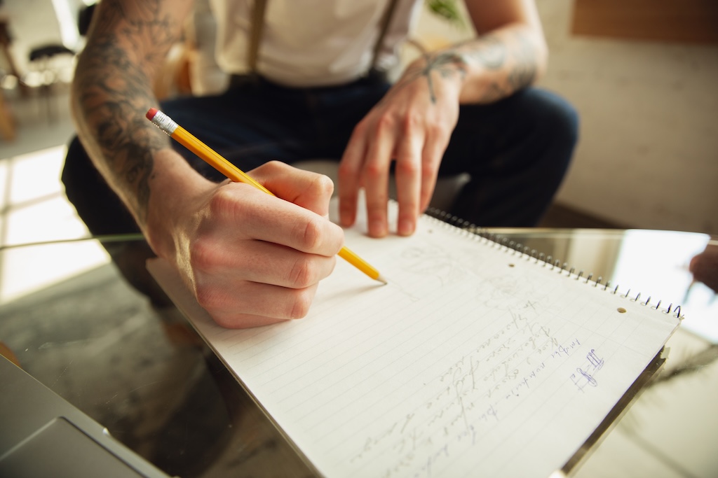 Close up of male hands writing on an empty paper on the table.