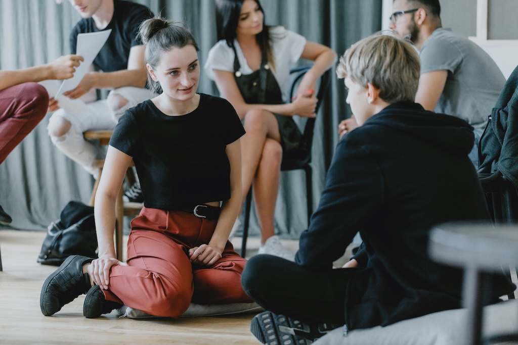 Young woman and man talking to each other during psychological role playing exercise in experiential therapy.