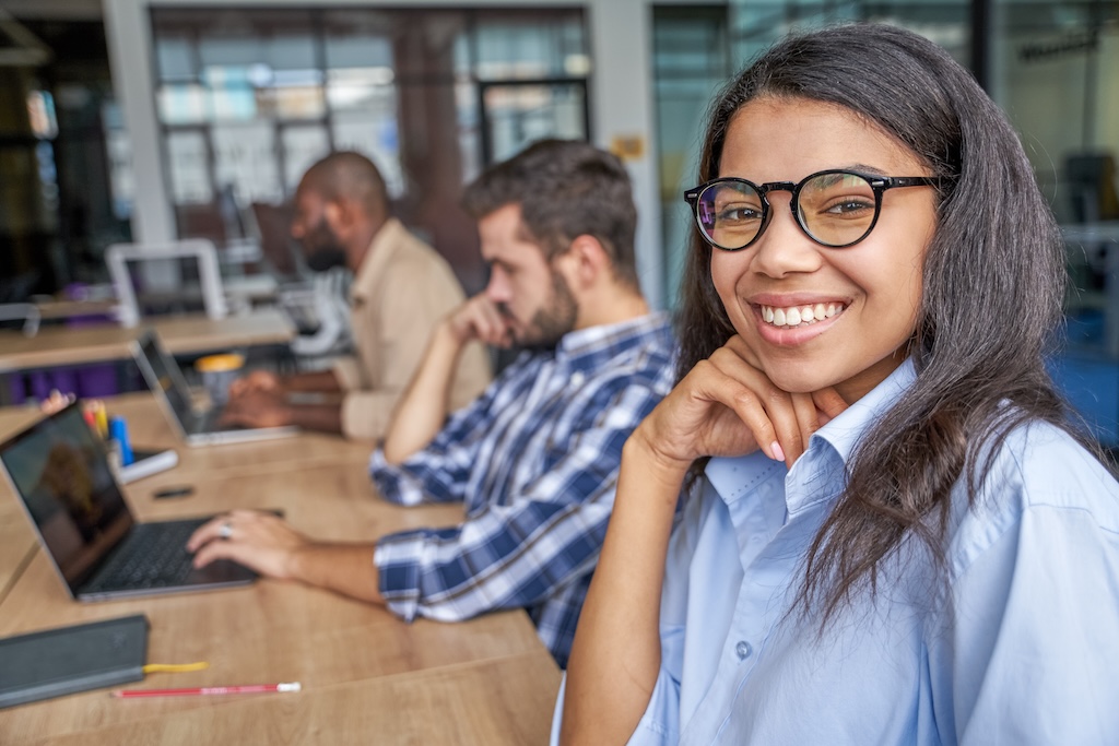 Smiling woman looking with happiness and working with other clients to build interpersonal skills.