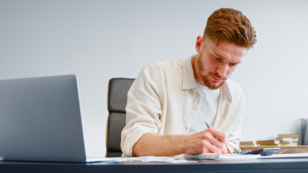 Young man sitting at a desk filling out job application as part of life skills class at rehab center.