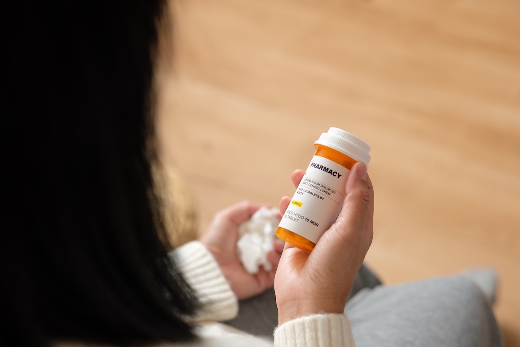 Woman reading pill prescription bottle