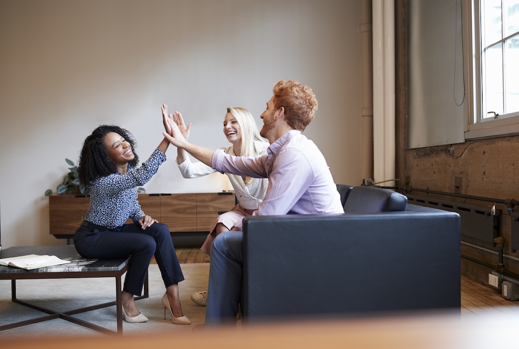 Three clients high five during group as they learn skills in socialization with peers.