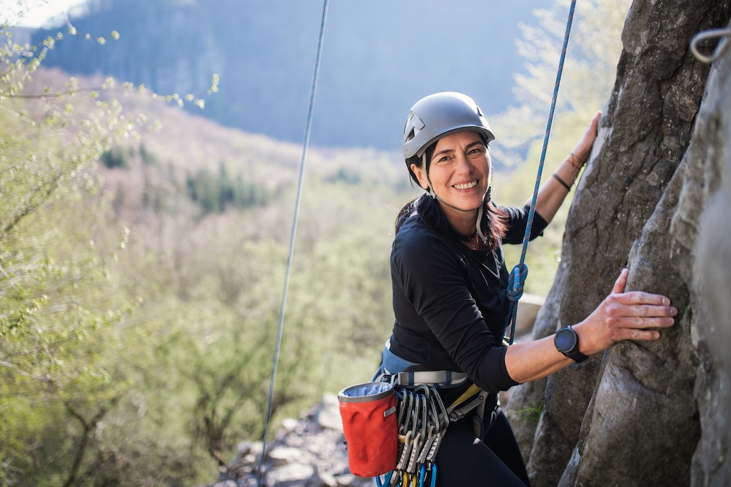 Portrait of woman climbing rocks andlooking at camera outdoors in nature,