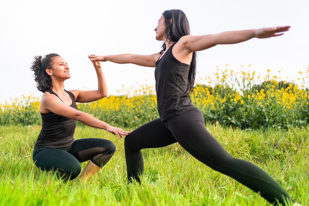 yoga teacher teaches student a position in green park