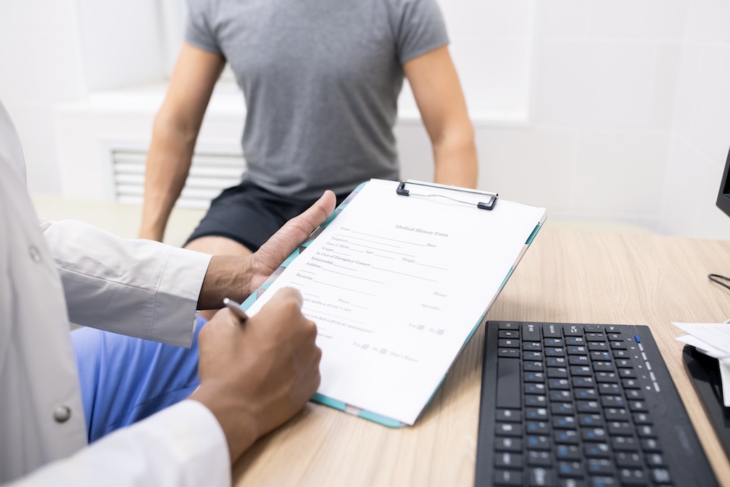 Clinician holding pen over medical document while filling in data of patient