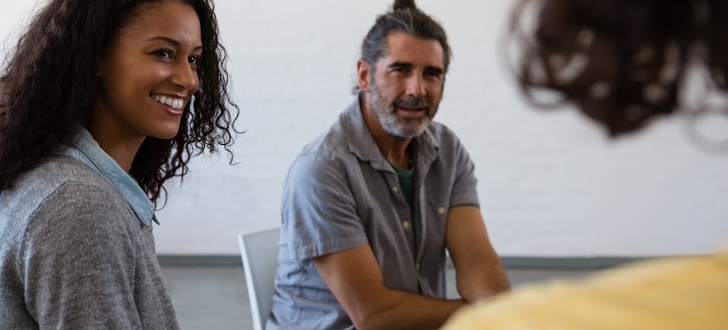 Friends looking at man while sitting on chair in clinical group